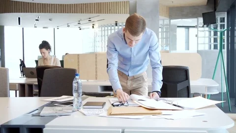 Young working businessman sort out working papers for analitic tasks Видео 73268591