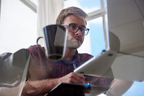 Young working man shot from under a glass table Stock Photos