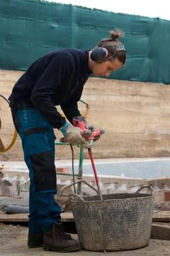 Young working man using drill mixing machine construction with headphones on Stockfoto's