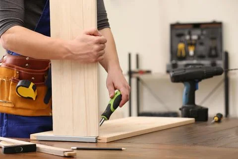 Young working man using screwdriver indoors, closeup with space for text. Hom Stock Photos