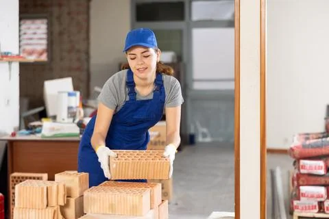 Young workwoman stacking bricks at construction site indoors Stock Photos
