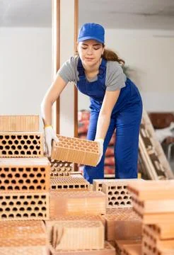 Young workwoman stacking bricks at construction site indoors 写真素材