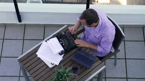 Young writer thinking, checking something on laptop while writing book on typewr 스톡 동영상 58946613