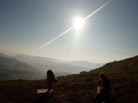 A young yogi pulls his hands toward the morning sun on the tops of the Stock Footage 77782995