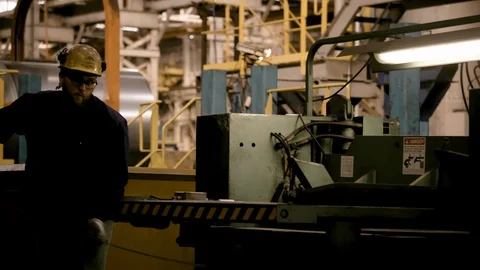 Younger man picks up steel off lathe and exists frame in Modern Factory Stock Footage 89944588