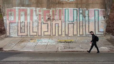 Younger man walking by a cement wall. Video stock 181160001