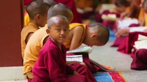 Youngest monk distracted while other young monks studying at the monastery Stock Footage 77443904