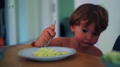 Youngster lifting forkful of spaghetti at the dining table at home, determi.. Stock Footage 340430552