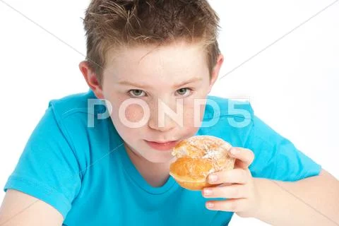 Youny boy eating a sugary doughnut. Stock Photos