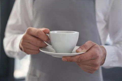 Your coffee, please. Cropped image of a man holding a cup of good coffee against Stock Photos