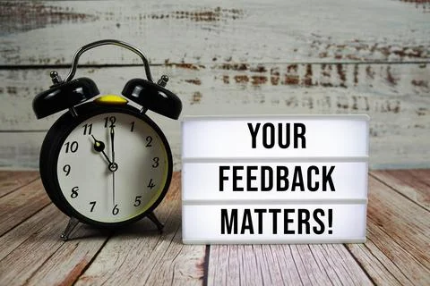 Your Feedback Matters! text on light box with alarm clock on wooden backgroun Stock Photos