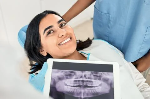 Your teeth have really improved. a dentist looking over a patients x-rays before Stock Photos