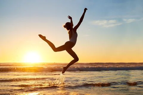 Youre free to be whoever. Shot of a young woman jumping into mid air against a Stock Photos