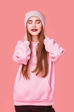 Youth fashion. Modern teen girl in a pink sweatshirt and a hat posing at stud Stock Photos
