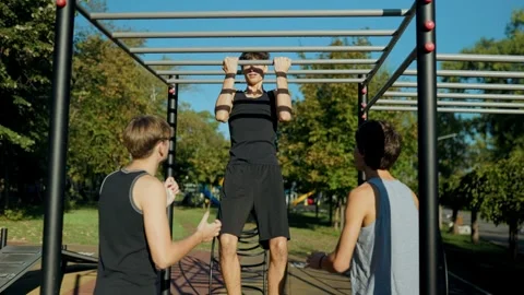 Youth group doing pull ups on monkey bars during outdoor team training. Stock Footage 346140460
