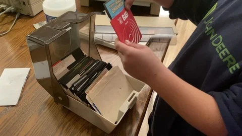 Youth inspects a old fashioned storage box of large floppy computer discs, Stock Footage 124065608