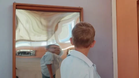 Youth observes own distorted image. Silent boy examines altered self in solitude Stock Footage 335299626