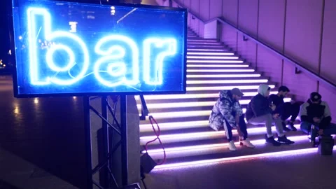 Youths on steps next to a Bar neon sign 6K Video stock 310399301