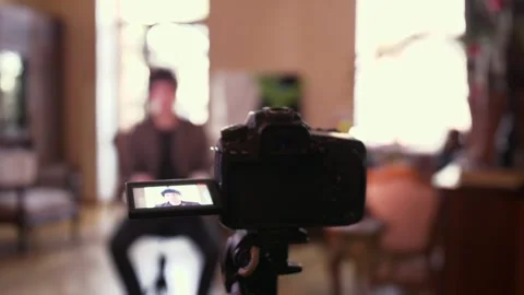 Youtuber recording a video of himself in a flat talking to his audience watching Video stock 232581601