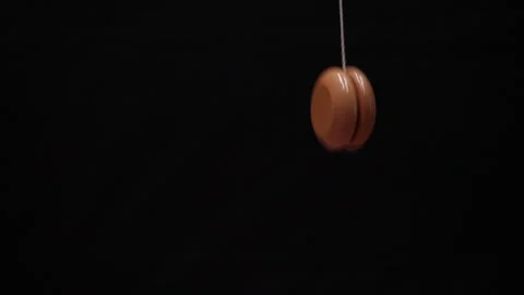 A yoyo going up and down through the frame on black background Stock Footage 235733196