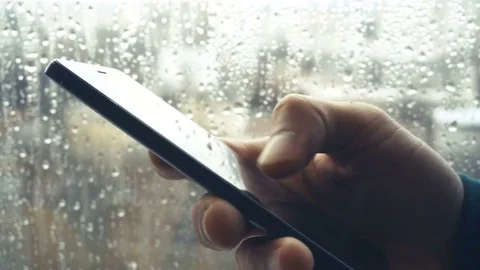 Ypung man browsing information on smartphone with drops on background Video stock 84258031