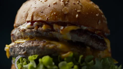 Yummy burger with double beef cutlet, melted cheese, lettuce and vegetables Video stock 131619480