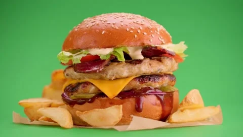 Yummy cheeseburger and fries rotation on a green screen background. Video stock 147292853