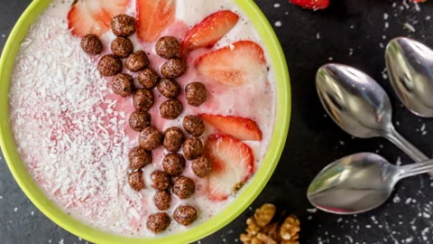 Yummy strawberries, flakes, coconuts are sinking in the foamy bl Stock Footage 101335630