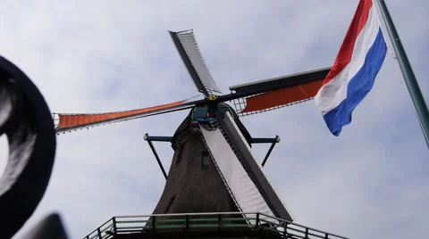 Zaanse Schans, Netherlands, windmill spinning in the wind with the national flag Stockbeeldmateriaal 60980968