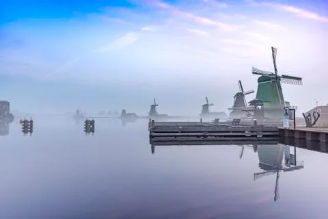 Zaanse Schans windmill reflection on the calm river water at the sunrise mome 库存照片