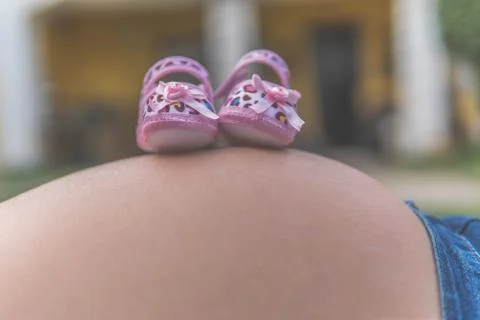 Zapatos de bebé, sobre la panza de su madre Stock Photos