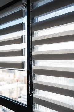 Zebra roller blinds on tall window with sunlight and urban city view background 스톡 사진