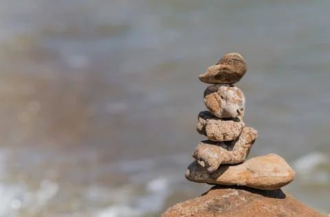 Zen concept. Object made of stone on the beach. Stone pyramid for meditation. Stock Photos