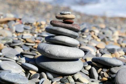 Zen practice of stacking colourful pebbles on a beach shore Stock Photos