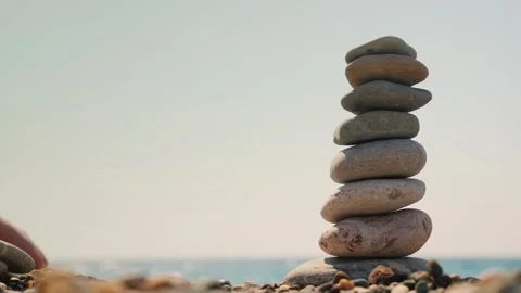 Zen rock balancing on beach shore with calm sea background. Stock Footage 334641673