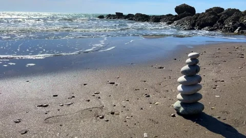 Zen stone cairn on sandy beach with ocean and rocks Stock Footage 310244134