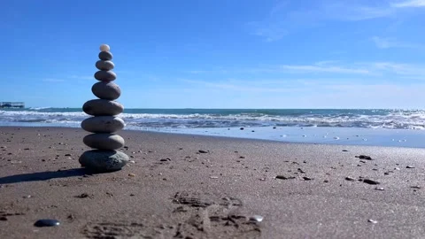 Zen stone tower on beach with ocean waves and blue sky Stock Footage 310244869
