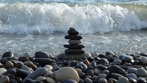 Zen stones stack on the beach with sea surf behind Stock Footage 77443554