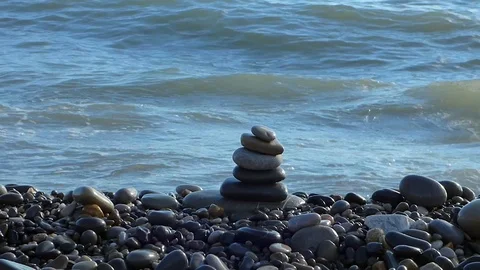 Zen stones stack on the beach with sea surf behind Stock Footage 77518558