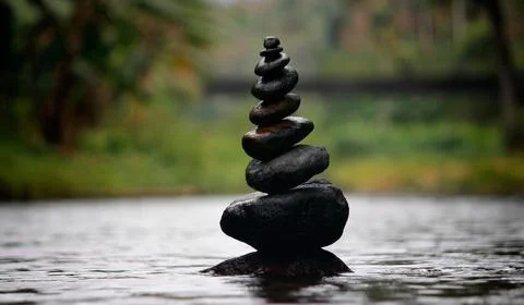 Zen stones stack from large to small in water and peaceful landscape background. Stock Photos