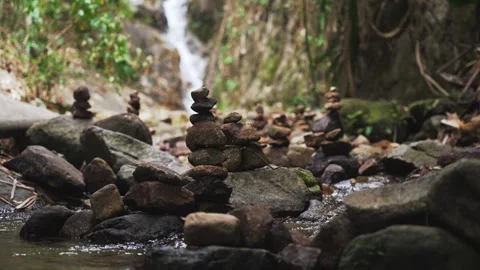 Zen-style stone stacks balanced in a clear stream of river water flowing from a Stock Footage 309274590