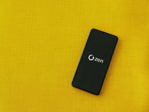 ZEN.COM app launch screen on smartphone on yellow fabric background Stock Photos