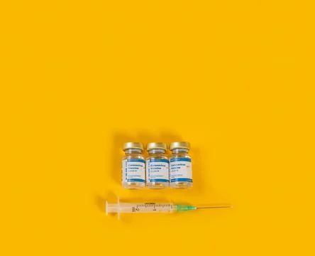 Zenith View of Three Coronavirus Vials And A Syringe On Yellow Background. Stock Photos