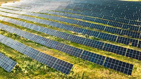 Zero-emission blue solar panels on a green field, drone view. Stock Photos