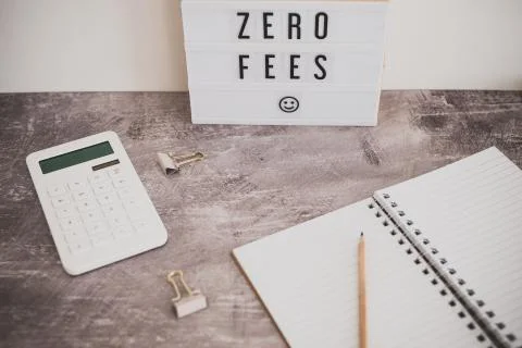 Zero fees message on lightbox surrounded by coins calculator Stock Photos