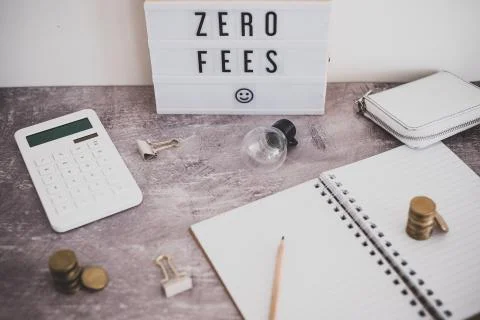 Zero fees message on lightbox surrounded by coins calculator Stock Photos