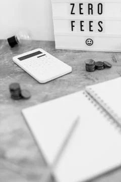 Zero fees message on lightbox surrounded by coins calculator Stock Photos