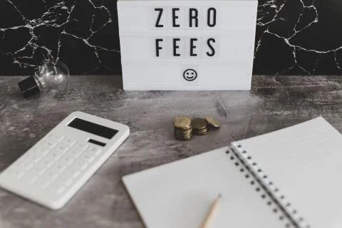 Zero fees message on lightbox surrounded by coins calculator Stock Photos