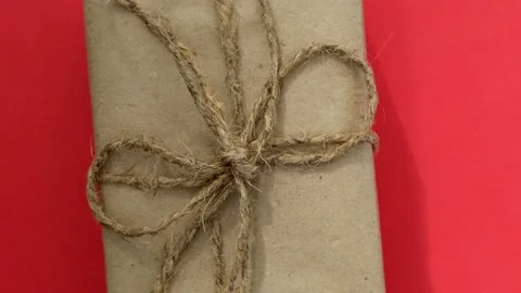 Zero waste Christmas gift in craft paper spins on a red background Video stock 218465653