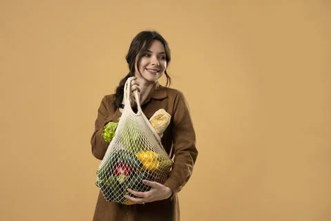 Zero waste concept. Happy young brunete girl holds a textile eco bag with Stock Photos